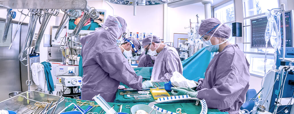Imagem de três profissionais da saúde em sala cirúrgica