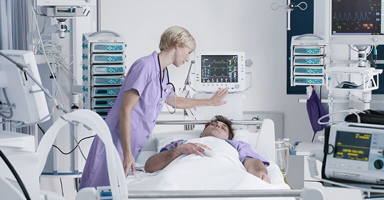 Medica checando o paciente em quarto cheio de equipamento de monitoramento